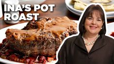 a woman standing in front of a plate of food with meat and potatoes on it