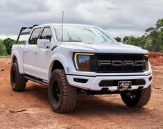 a white truck parked on top of a dirt field