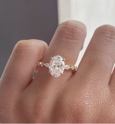 a woman's hand with a diamond ring on top of her finger, showing the center stone