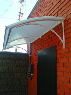 an awning on the side of a red brick building next to a black door