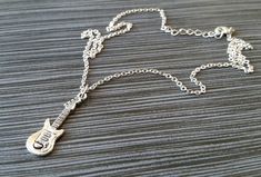 "Personalized Silver Guitar Necklace! A detailed three dimensional electric guitar charm on a bright silver chain makes the perfect gift for you or your favorite musician. The guitar charm is made from zinc alloy and measures 30 mm by 10 mm. The chain is silver plated and measures 16\" or 18\" with a 1\" extender. You can also personalize your necklace with a .5\" silver plated disc stamped with the initial of your choice (see last picture). To order your necklace WITHOUT a custom stamped initia Silver Music-themed Metal Necklace, Nickel-free Silver Music-themed Necklaces, Silver Rock Style Necklace Gift, Silver Rock Style Necklace As Gift, Silver Rock Style Necklace For Gift, Music Necklaces, Guitar Necklace, Silver Trumpet, Silver Guitar