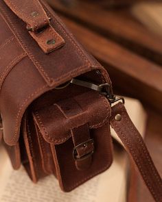 a brown leather bag sitting on top of an open book