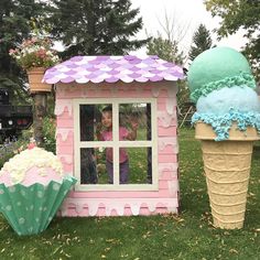 two ice cream cones are in front of a pink and blue building with an ice cream cone on top