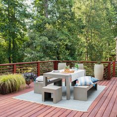 a table and chairs on a deck with trees in the background