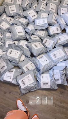 a pile of bags sitting on top of a wooden floor next to a pair of orange shoes