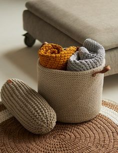 a crocheted basket with two slippers on the floor next to a couch