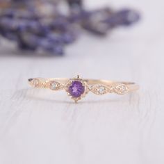 a gold ring with an amethorate and diamonds on it, next to lavender flowers