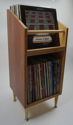 a record player stand with many records on it's sides and an electronic device in the top shelf