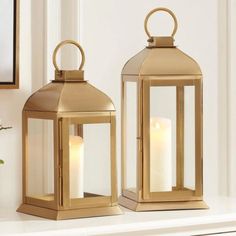 two gold lanterns sitting on top of a white mantle