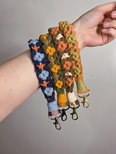 the hand is holding three bracelets with flowers on them and two keys attached to each other