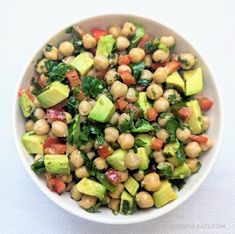 a white bowl filled with chickpeas, avocado and spinach salad