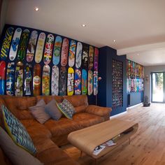 a living room filled with furniture and lots of skateboards on the wall