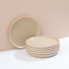 a stack of white plates sitting on top of a table next to a pink wall