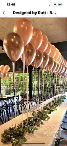 there is a long table with balloons and greenery on the tables in front of it