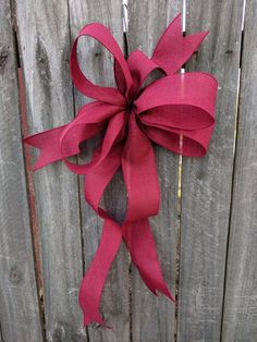 a red bow hanging on the side of a wooden fence