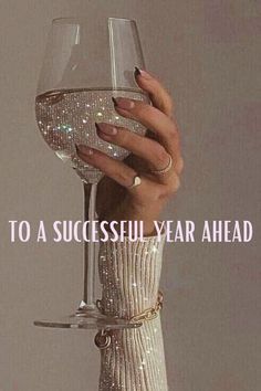 a woman's hand holding a wine glass with the words to a successful year ahead