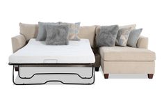 a couch with pillows and a pull out bed in front of it on a white background