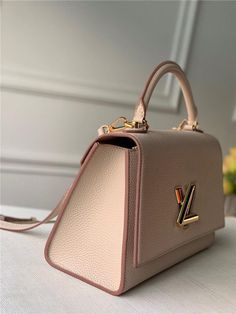 For Winter 2020, Louis Vuitton introduces the Twist One Handle handbag. This structured bag in Taurillon leather has an elegant top handle for hand carry as well as a detachable shoulder strap for crossbody carry. The Twist’s iconic turn-lock, first seen on the Pochette Trapeze in 1988, completes the design. The bag’s interior leather lining brings vibrant color. Detailed Features 8.3 x 11.4 x 4.7 inches (length x Height x Width) Greige Taurillon leather Taurillon-leather trim Cowhide-leather li Structured Bag, Lv Bags, Louis Vuitton Fashion, Louis Vuitton Twist, Gucci Bags, Vuitton Bag, Bag Handle, Replica Handbags, Handle Bag