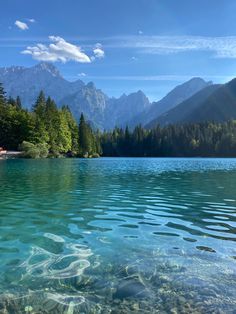 the water is crystal blue and clear with mountains in the background