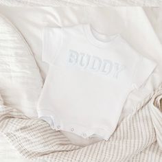 "Celebrate your sweetie with this piece featuring a white embroidered lettered text on a white colored romper. This sweet piece is the perfect romper for baby. The design is made on a 100% cotton fabric, light sweatshirt material. It is cozy soft and perfect for staying cuddly. This romper is oversized in style in a baby sweatshirt bubble romper design. Select the words you would like in the \"personalization\" section. Your word of choice must be under 7 in order to fit across the chest. Please White Short Sleeve Cotton Bodysuit, White Short Sleeve Bodysuit With Letter Print, White Short Sleeve Onesie For Baptism, Personalized Cotton Onesie For Baptism, Basic White Cotton Onesie, White Letter-printed Short Sleeve Bodysuit, Basic White Short Sleeve Onesie, Cotton Baptism Onesie With Short Sleeves, White Cotton Crew Neck Onesie