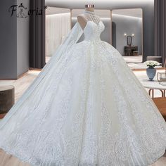 a white wedding gown on display in a room with mirrors and furniture, including a table