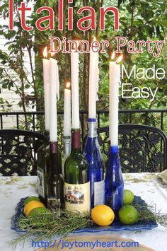 a table topped with bottles of wine and lemons next to candles on top of a table