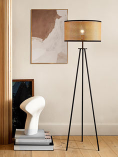 a floor lamp sitting on top of a wooden floor next to a white chair and book