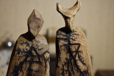 two wooden sculptures with black ink on them