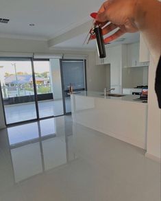 a person holding a remote control in their hand near a kitchen and living room with sliding glass doors