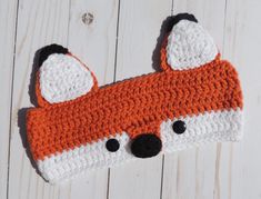 an orange and white crocheted hat with a fox face on it's side