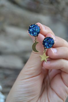 PLEASE read my shop announcement before placing an order so you know what to expect right now. Plus, when ordering from outside Europe, don't forget to provide a phone number for the courier to ensure the fastest and smoothest delivery. Sparkling peacock / sapphire blue druzy stud earrings with golden brass dangling moon and star. Dainty and edgy at the same time, elegant Boho Chic style. Antiqued bronze lightweight posts, rubber backings Cabochon base is about 12 mm, 0.47 inches Quality sinthet Blue Star Charm Drop Earrings, Blue Drop Earrings With Star Charm, Peacock Sapphire, Mismatch Earrings, Moon And Star Earrings, Moon Studs, Druzy Earrings, Mismatched Earrings, Gold Moon