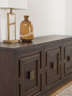 a large wooden cabinet with drawers and a lamp on it's sideboard in a living room