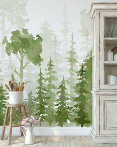 a room with green trees painted on the wall and a white vase filled with flowers