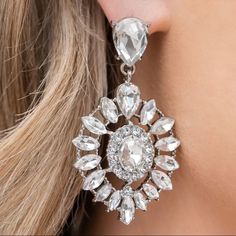 a close up of a woman's ear wearing large earrings with clear stones on them