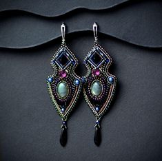 a pair of earrings with beaded details on them sitting on top of a black surface