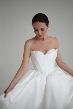 a woman in a white dress is posing for the camera with her hands on her hips