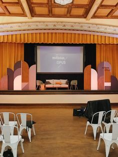 an empty auditorium with chairs and a projector screen