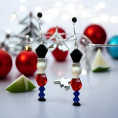 red, white and blue beaded earrings with christmas ornaments in the background on a table