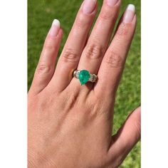 a woman's hand with a ring on it and a green stone in the middle