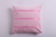 a pink pillow with sequins and stripes on it sitting on a white surface