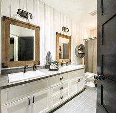 a bathroom with two sinks, mirrors and a toilet