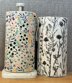 two toilet paper rolls sitting next to each other on a wooden table with a gray wall in the background