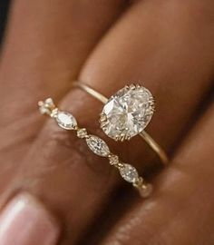 a woman's hand holding a ring with a diamond on it and two diamonds in the middle