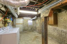 an unfinished room with exposed pipes and dryer boxes on the ceiling, next to a washer and dryer