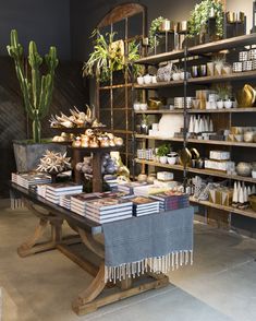 a table with some plants on it in front of shelves filled with books and other items