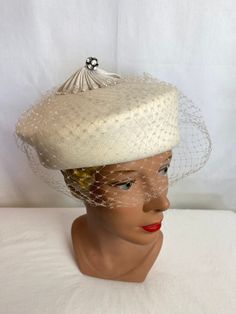 "This hat is a few shades of white or should I say off white? It's very retry, a felted wool base with semi structured netting in the front. A kind of ornamental centerpiece on the top.  It looks very nice. Under closer inspection, it does have some minor issues. A couple moth nibbles it appears, and a tiny spot or 2. I did lint roll it and brush it a little gently, but it's a white so it likely isn't as white as it once was, it's hard to say.  The netting seems to be decent however I did notice Felt Hats, Pillbox Hat, Retro Wedding, Bone White, Pill Boxes, Shades Of White, Felt Hat, Felted Wool, Hat Pins