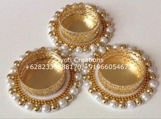 three gold and white beaded buttons with pearls on them, sitting on a table