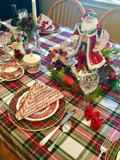 a table set for christmas dinner with santa clause on the top and plaid table cloth