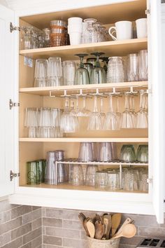 an open cabinet filled with glasses and other kitchen items