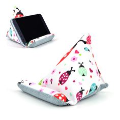 a cell phone and pillow sitting next to each other on a white surface with ladybug designs